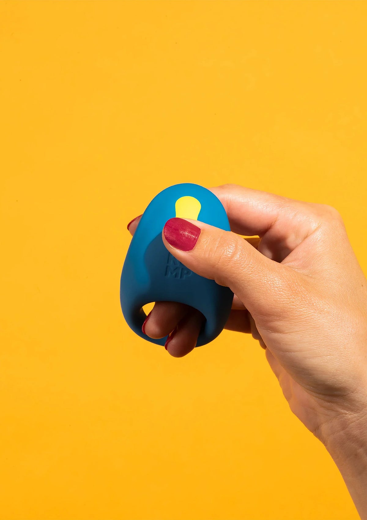 Blauwe vibrerende cockring met gele inzet en ronde opening, met vinger ingedrukt