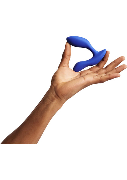 Marineblauwe We-Vibe Vector + vibrerende plug in hand, gebogen uiteinde zichtbaar.