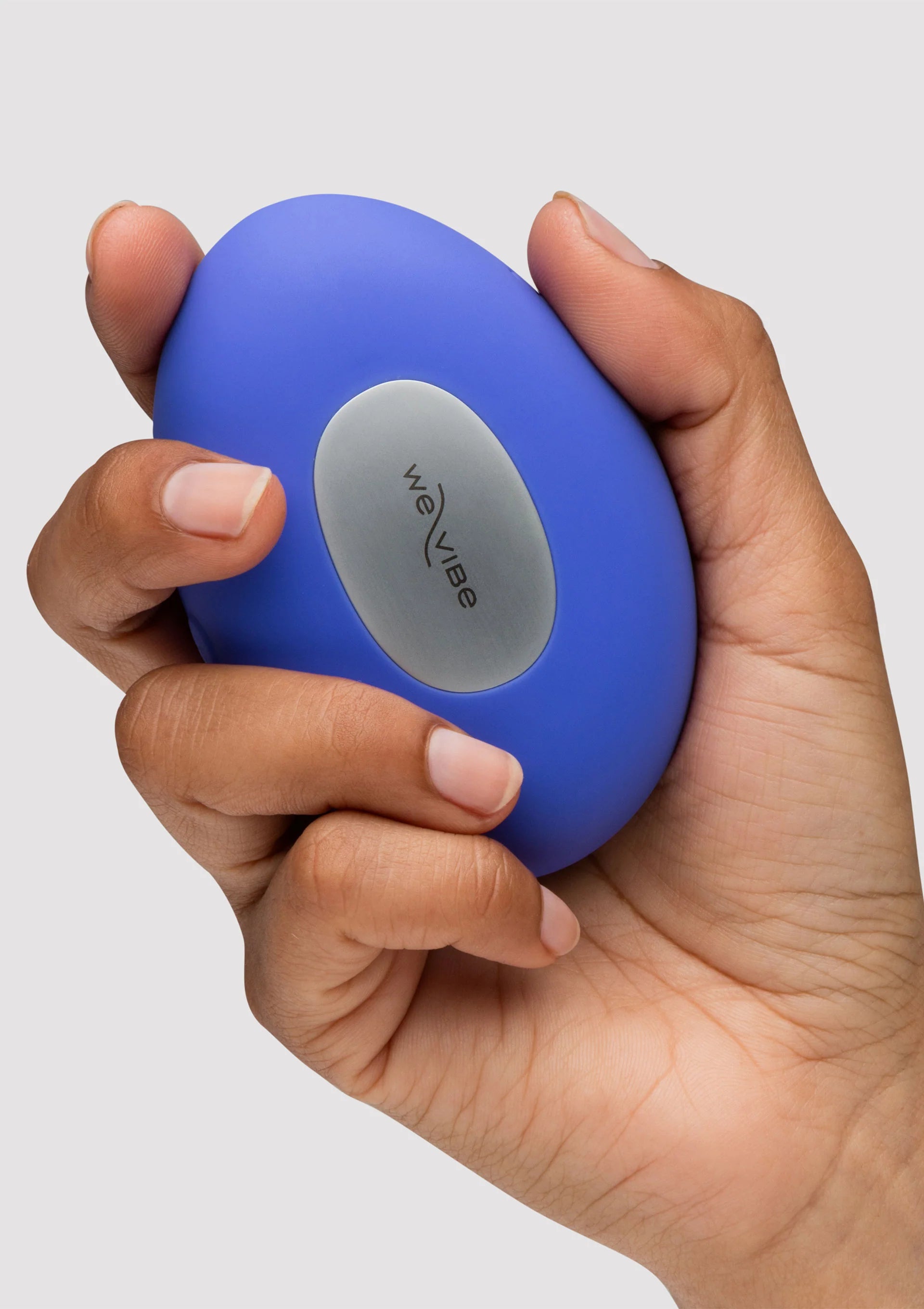 blauwe compacte vibrator met grijs bedieningsvlak en weVibe-opdruk, in hand