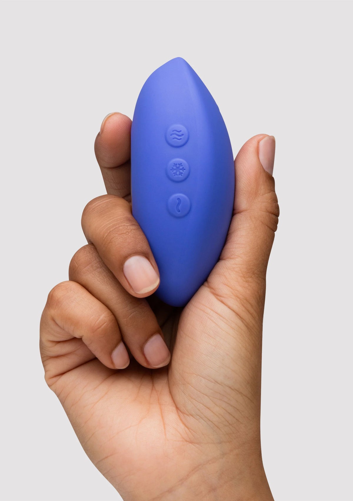 blauwe ovale vibrator met ronde bedienknoppen aan de zijkant, in hand