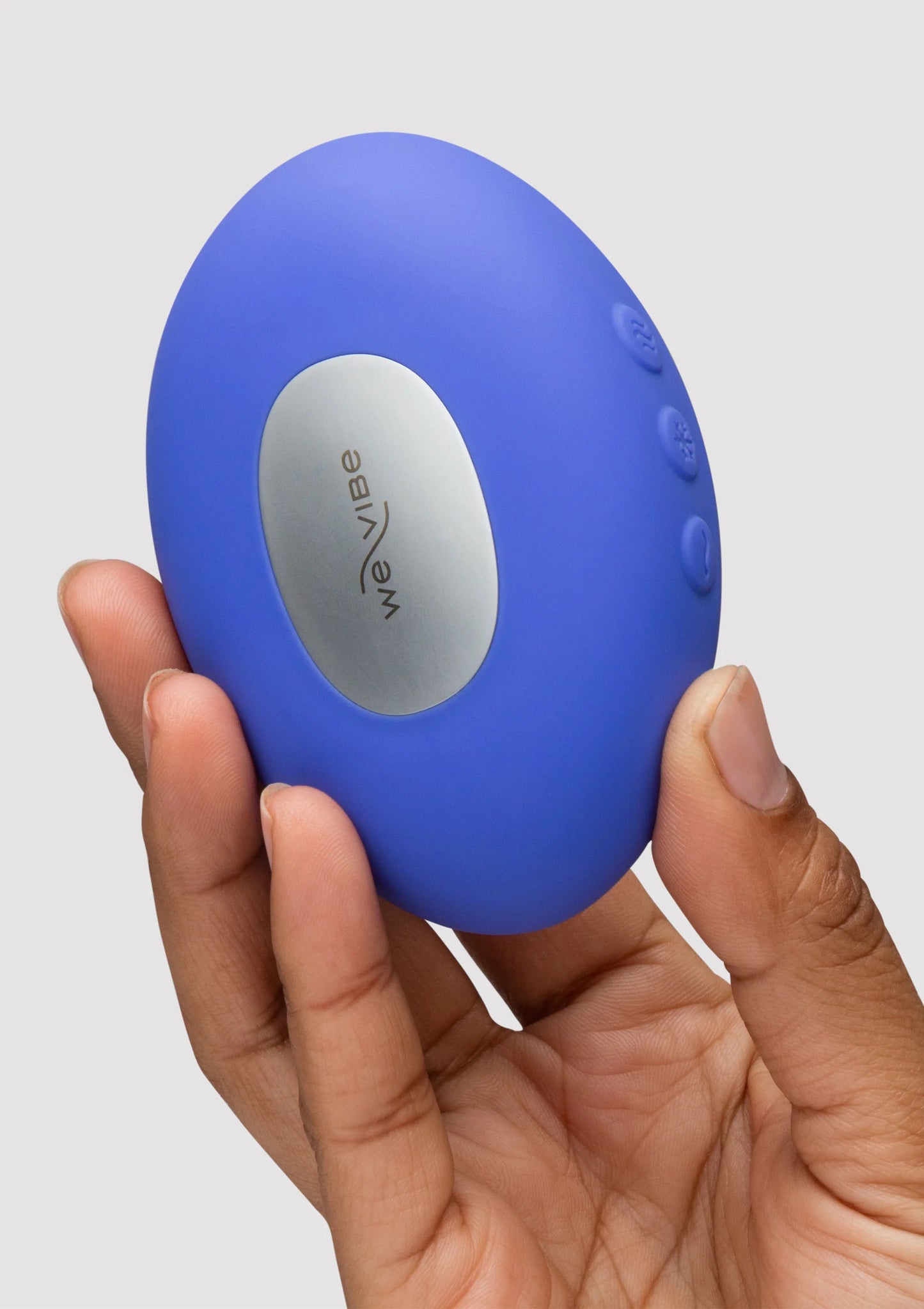 blauwe vibrator met grijs ovaal bedieningspaneel en weVibe-logo, close-up in hand