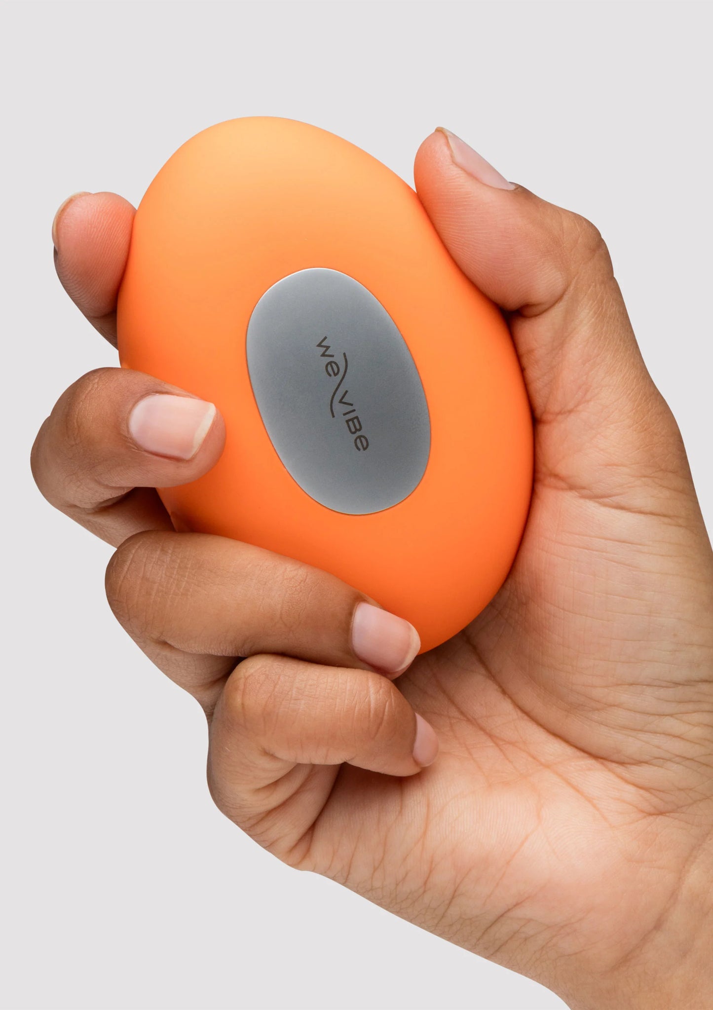 Oranje Temp massager in hand, grijze ovale bedieningsknop met weVibe