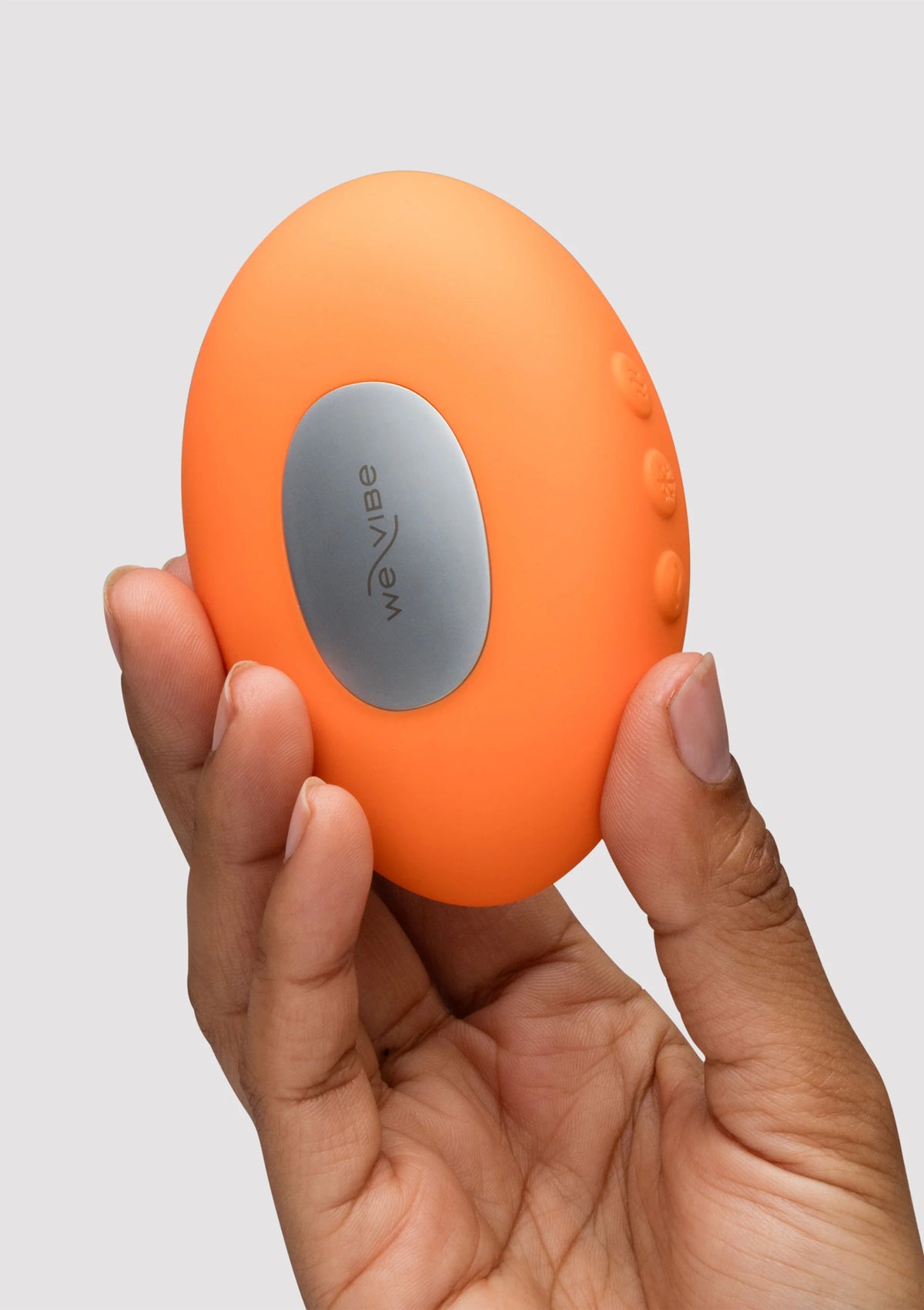 Oranje Temp massager met grijze ovale knopvlak, vastgehouden in handen