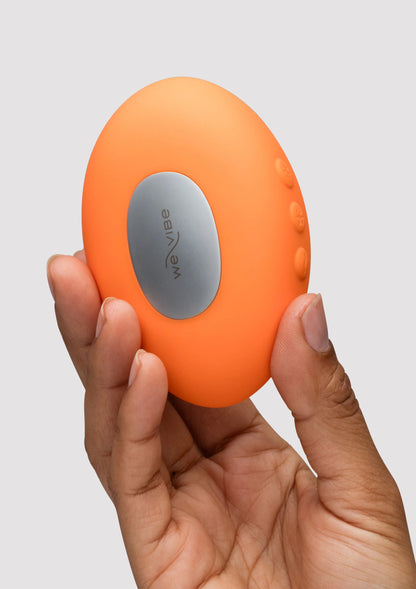 Oranje Temp massager met grijze ovale knopvlak, vastgehouden in handen