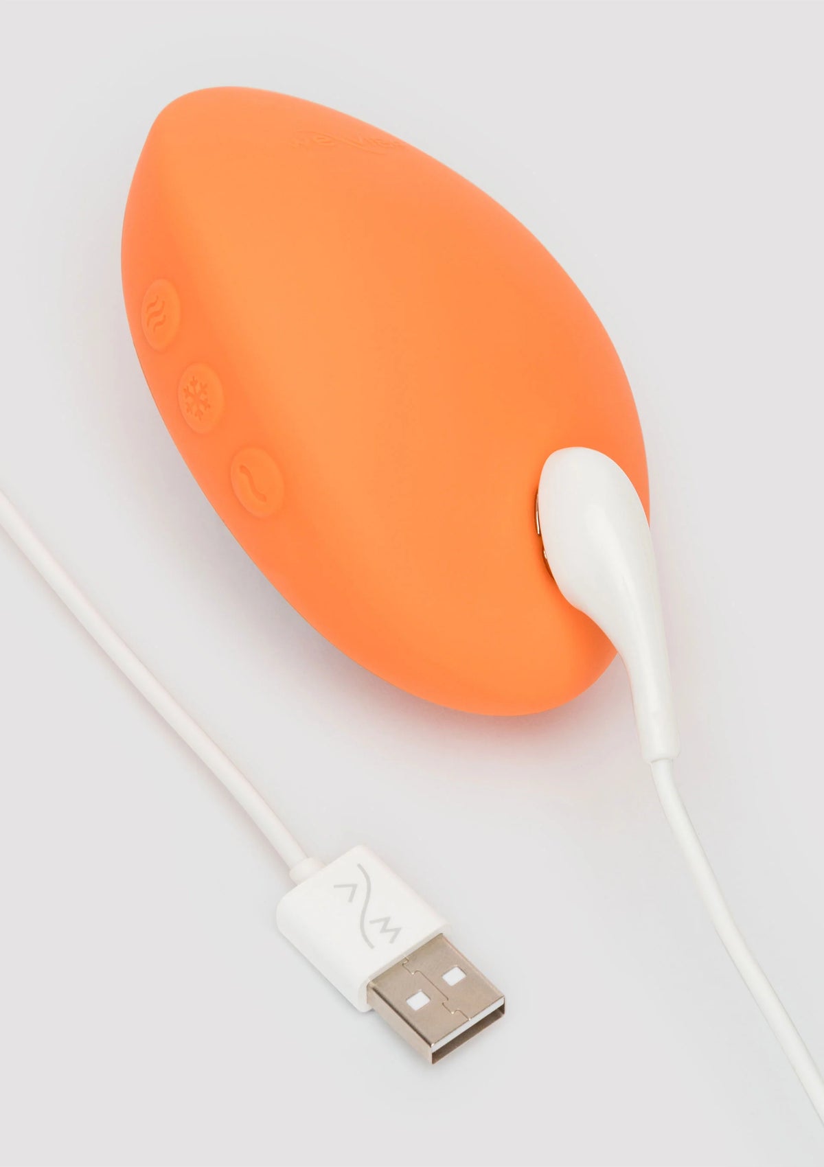 Oranje Temp massager op tafel met USB-kabel en witte stekker