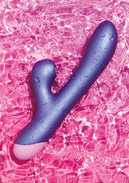 Blauwe konijnenvibrator met waterdruppels, liggend op roze waterpatroon.
