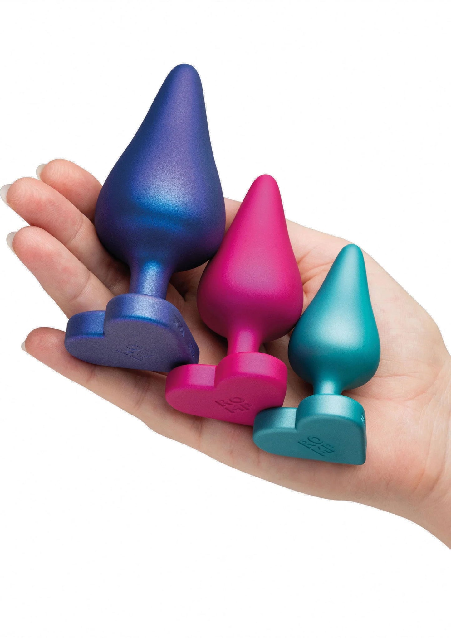 Anale trainingsset vastgehouden in hand: vier conische plugs in blauw, roze en teal.