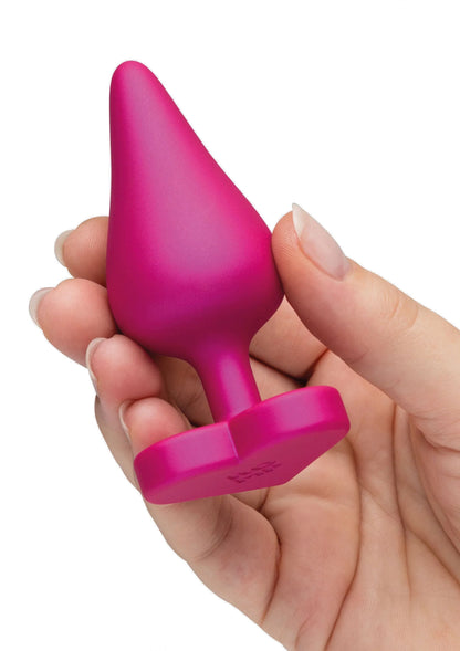 Anale trainingsset in hand: roze conische plug met brede voet en staart.