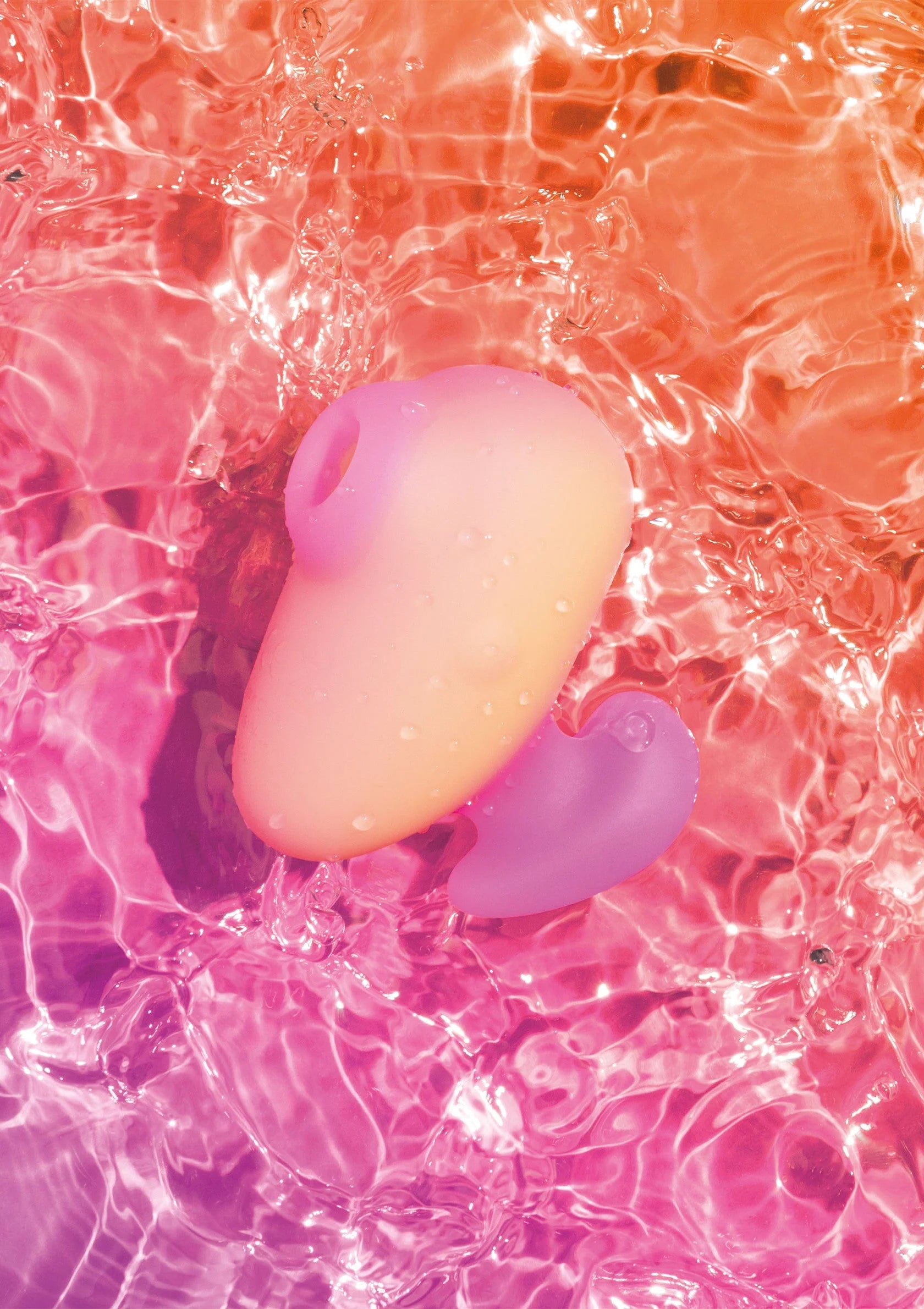 Roze vibrator in water met paars hulpstuk, onder schuimende belletjes