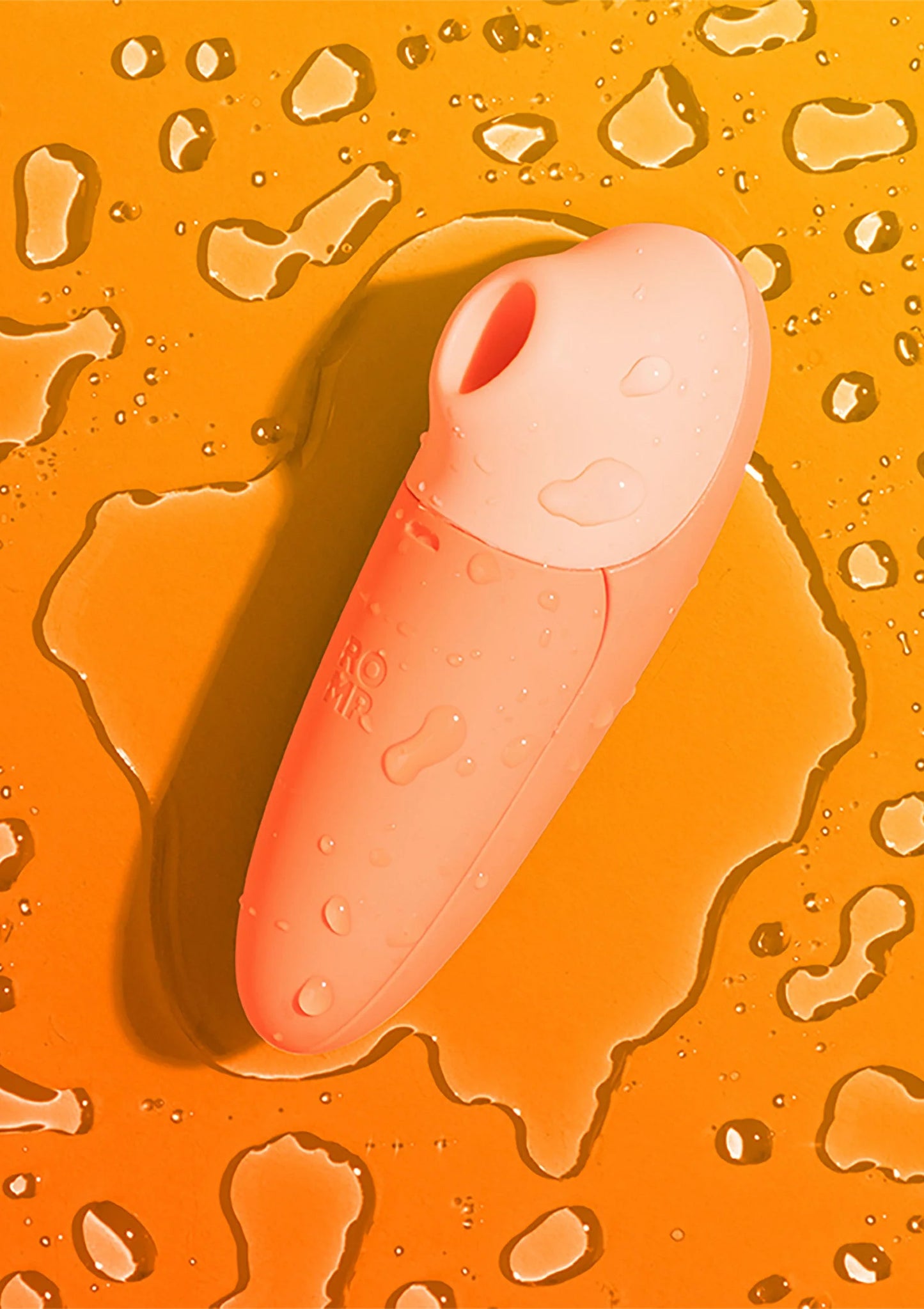 Oranje stimulatieapparaat met waterdruppels op het oppervlak