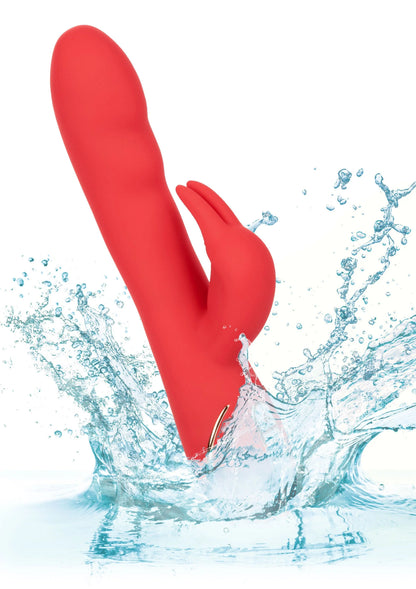 Rode verwarmde siliconen konijn-vibrator in water met spatten rond het apparaat.
