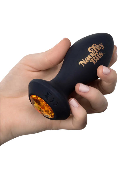 Zwarte siliconen anale plug met oranje glanzende tip, vastgehouden in een hand.