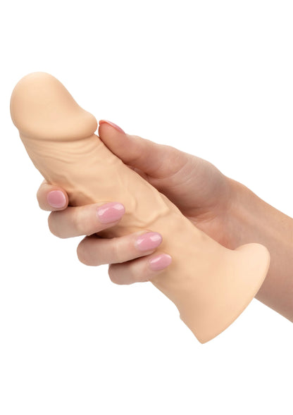 Beige siliconen verlengstuk in zwart W-harnas, close-up met hand