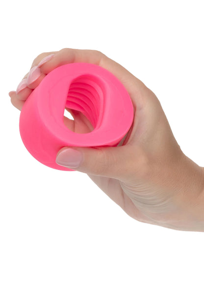 Hand die een roze siliconen ring vasthoudt; holle opening en ribbelstructuur zichtbaar.