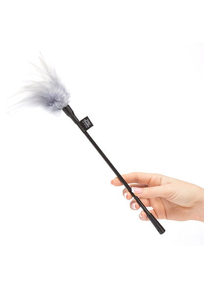 Veer-tickler met lichtgrijze pluim en zwarte steel; hand houdt het uiteinde vast