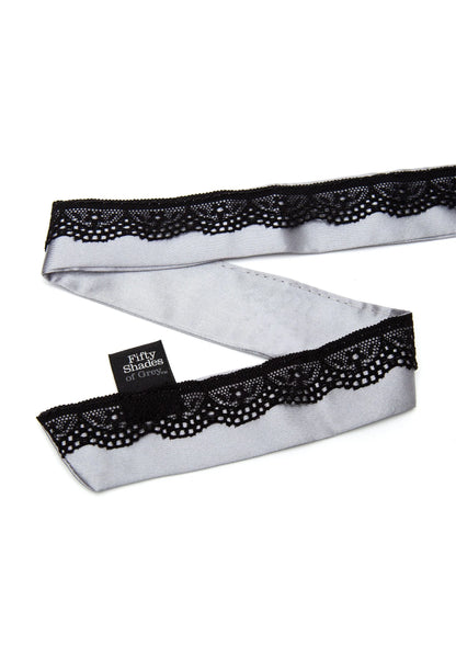 Zwarte kant over satijnen chokerband met ingebed label, close-up
