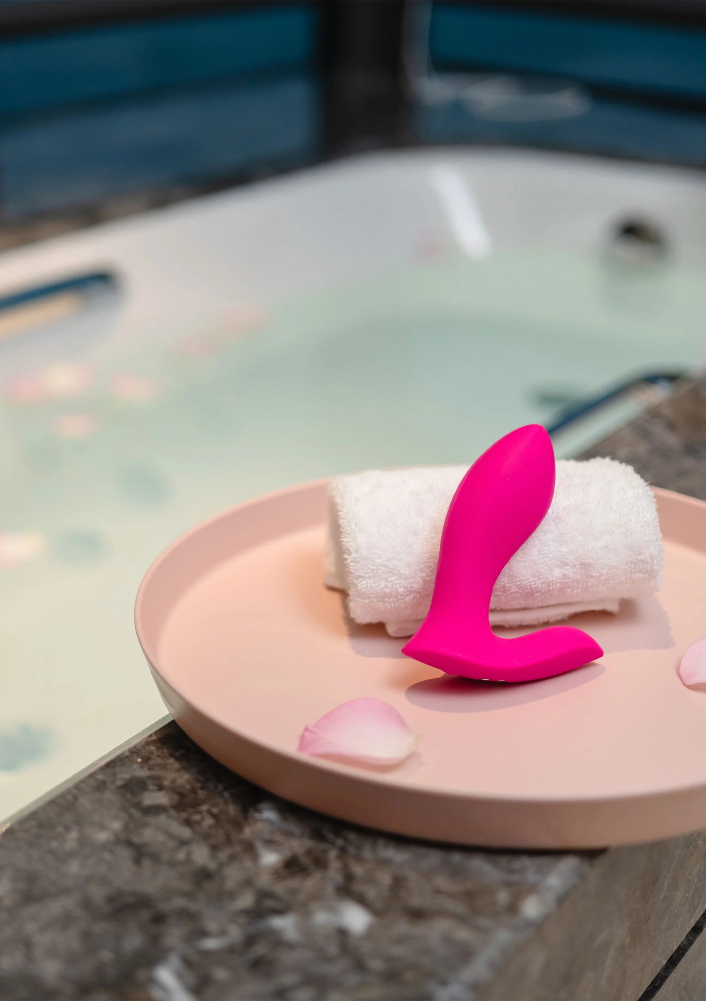 Roze koppelvibrator met twee uiteinden op een opgerolde badhanddoek