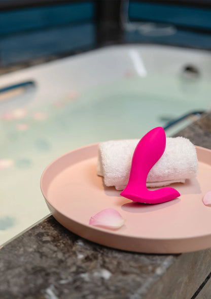 Roze koppelvibrator met twee uiteinden op een opgerolde badhanddoek
