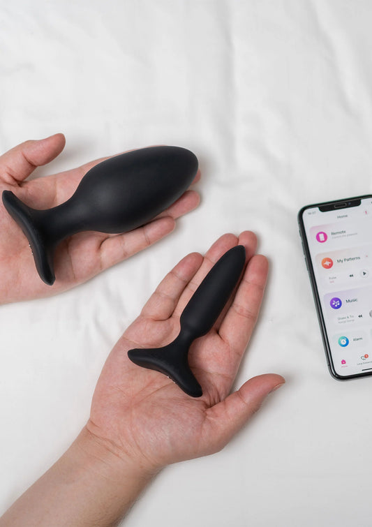 Zwarte buttplug in handen, met brede voet en smalle steel