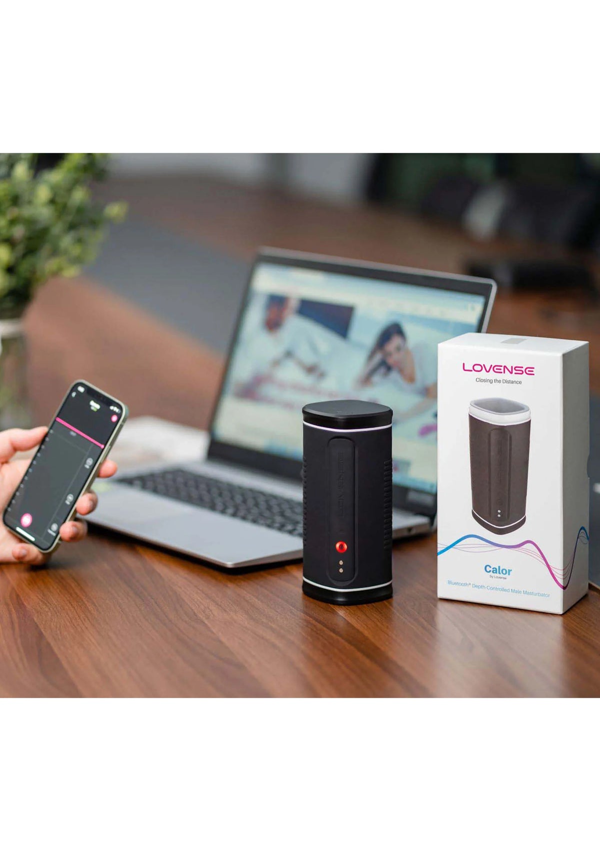 Zwarte Lovesense Calor masturbator op tafel met smartphone en laptop in beeld