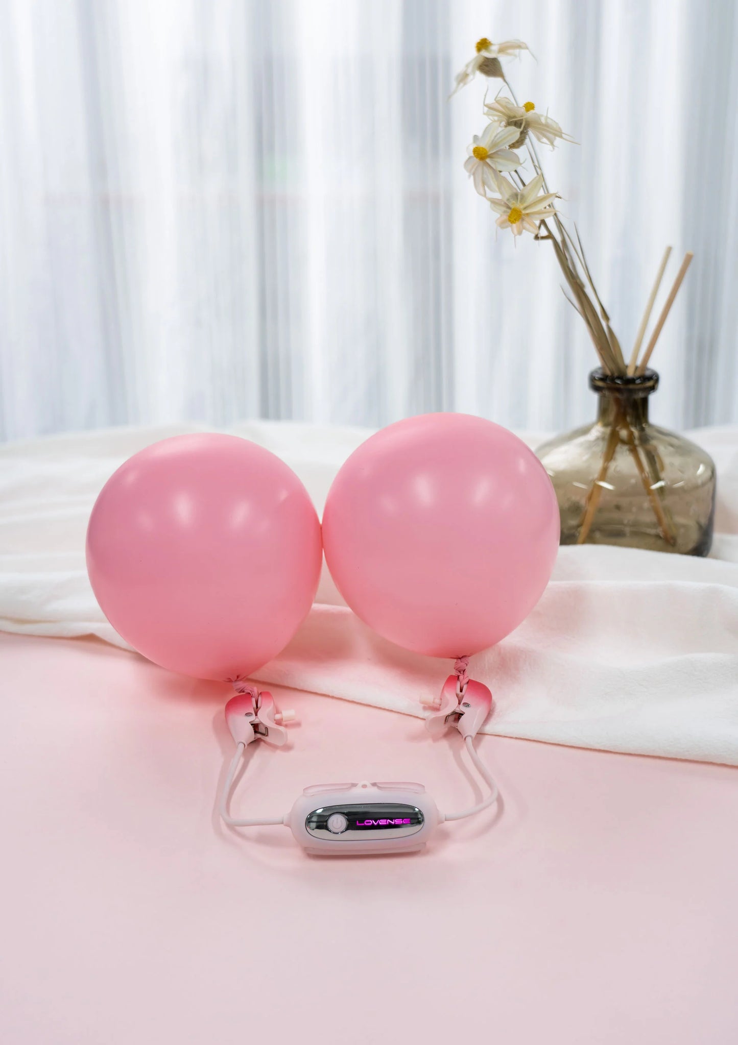 Roze nippelklemmen op twee roze ballonnen met bedienunit op voet
