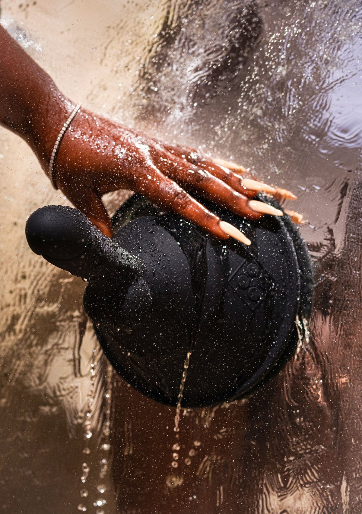 Zwarte siliconen attachment op hand in water met spatten