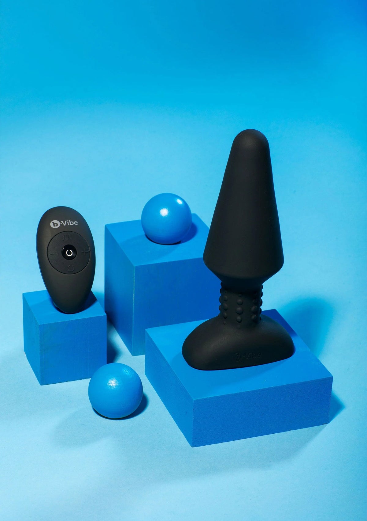 Zwarte rimming plug op blauwe set-tray met afstandsbediening op de achtergrond.