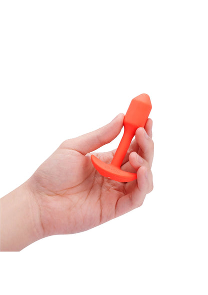 Trillende snug plug van B-Vibe, oranje plug vastgehouden in een hand