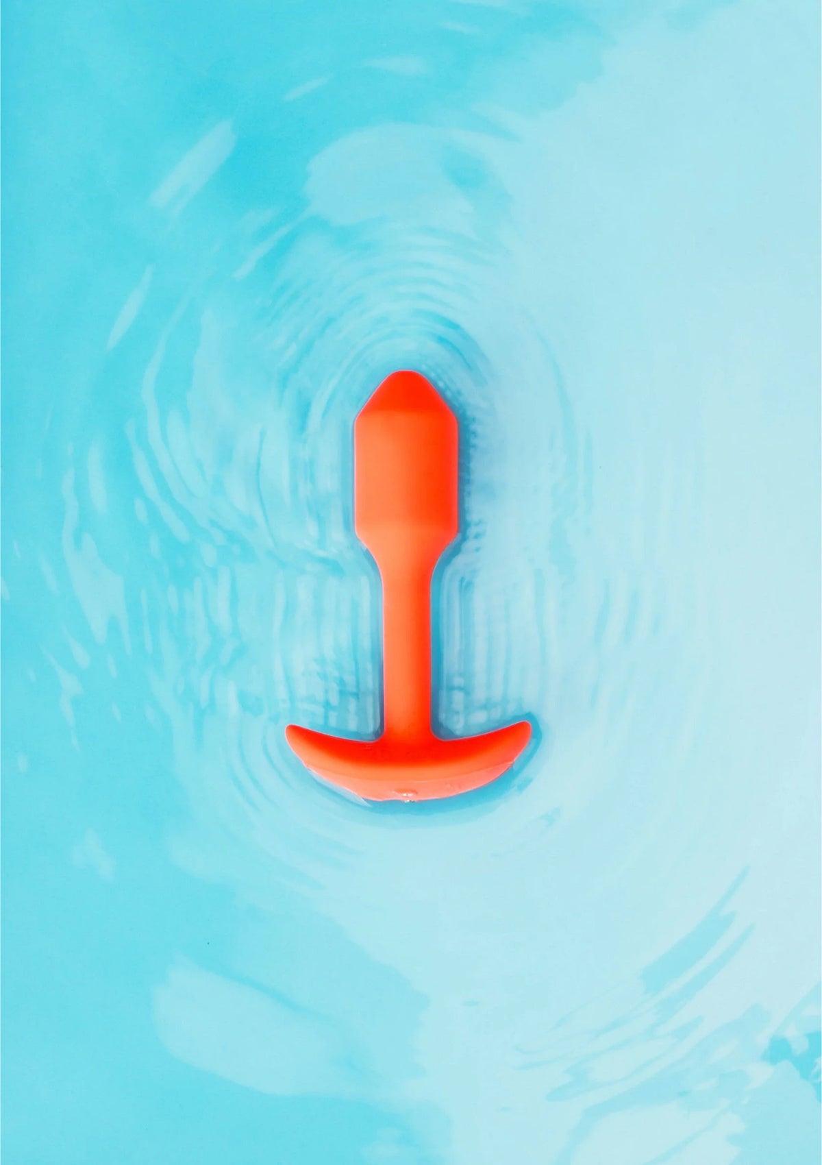 Trillende snug plug van B-Vibe, oranje plug in water met bubbels