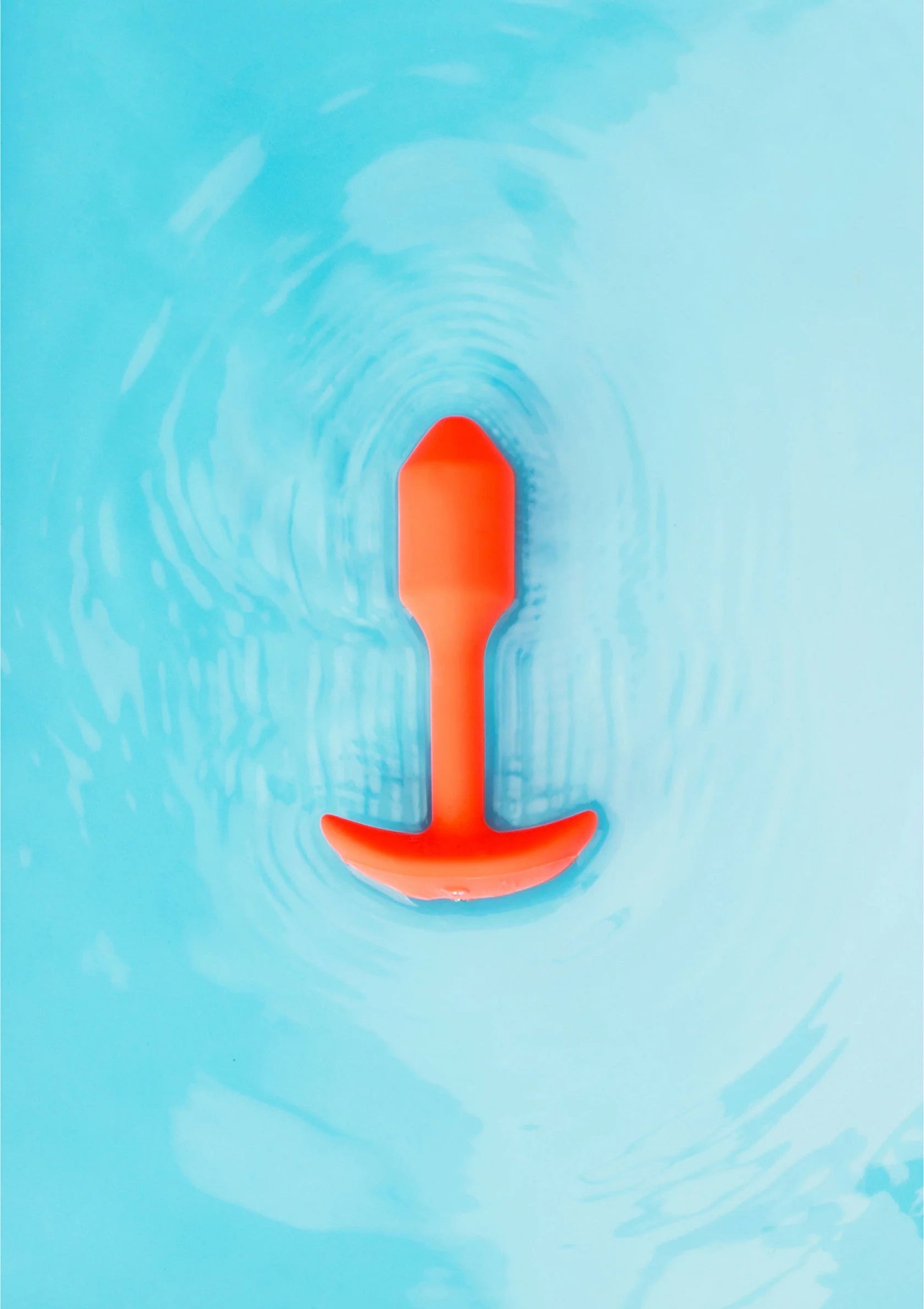 Trillende snug plug van B-Vibe, oranje plug in water met bubbels