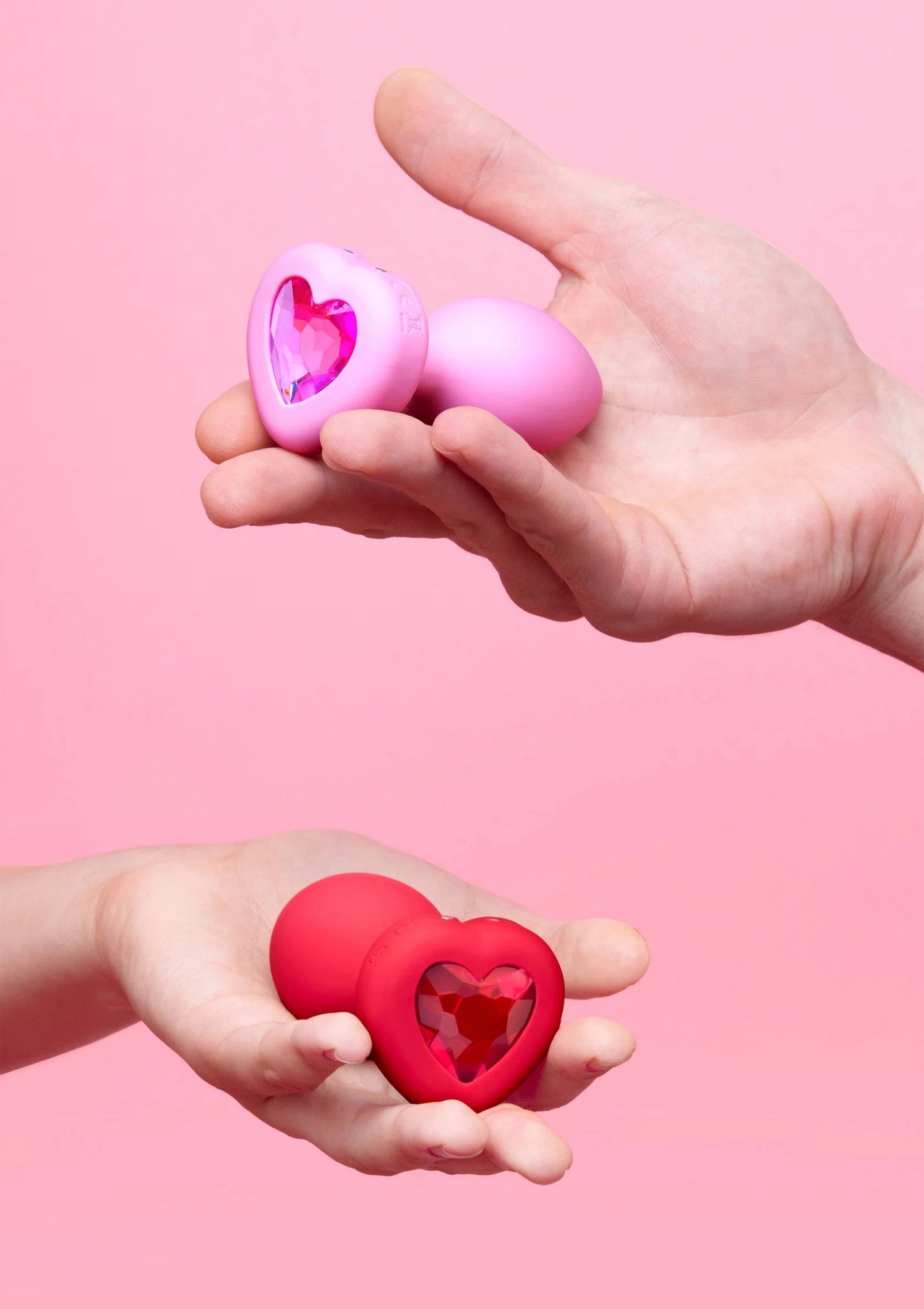 Roze hartvormige vibrerende plug met hartvormig venster, in handen