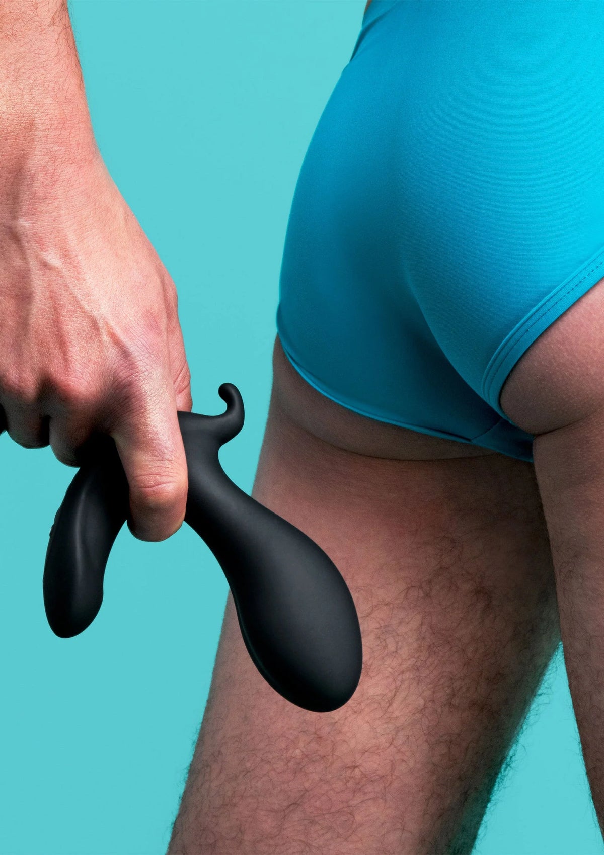 Zwarte siliconen anale plug B-Vibe met brede kop, hand plaatst op onderlichaam
