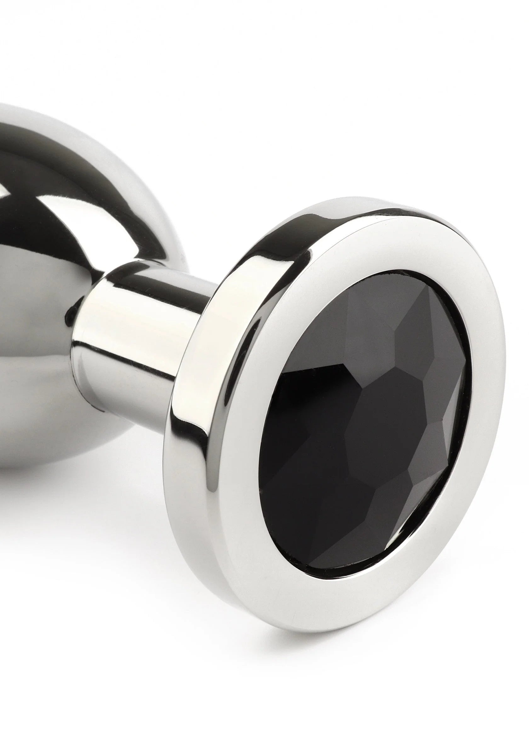 Anale plug close-up: zwarte ovale steen in metalen rand, gepolijste zilverkleur