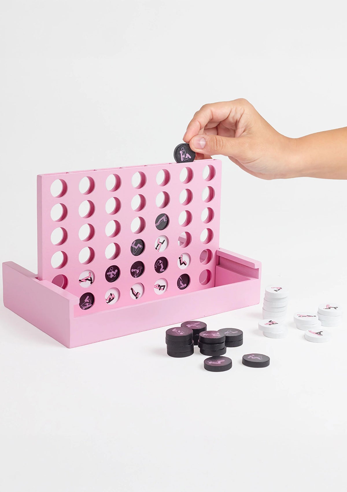 Hand boven de roze rasterplank met zwarte en witte speelschijven