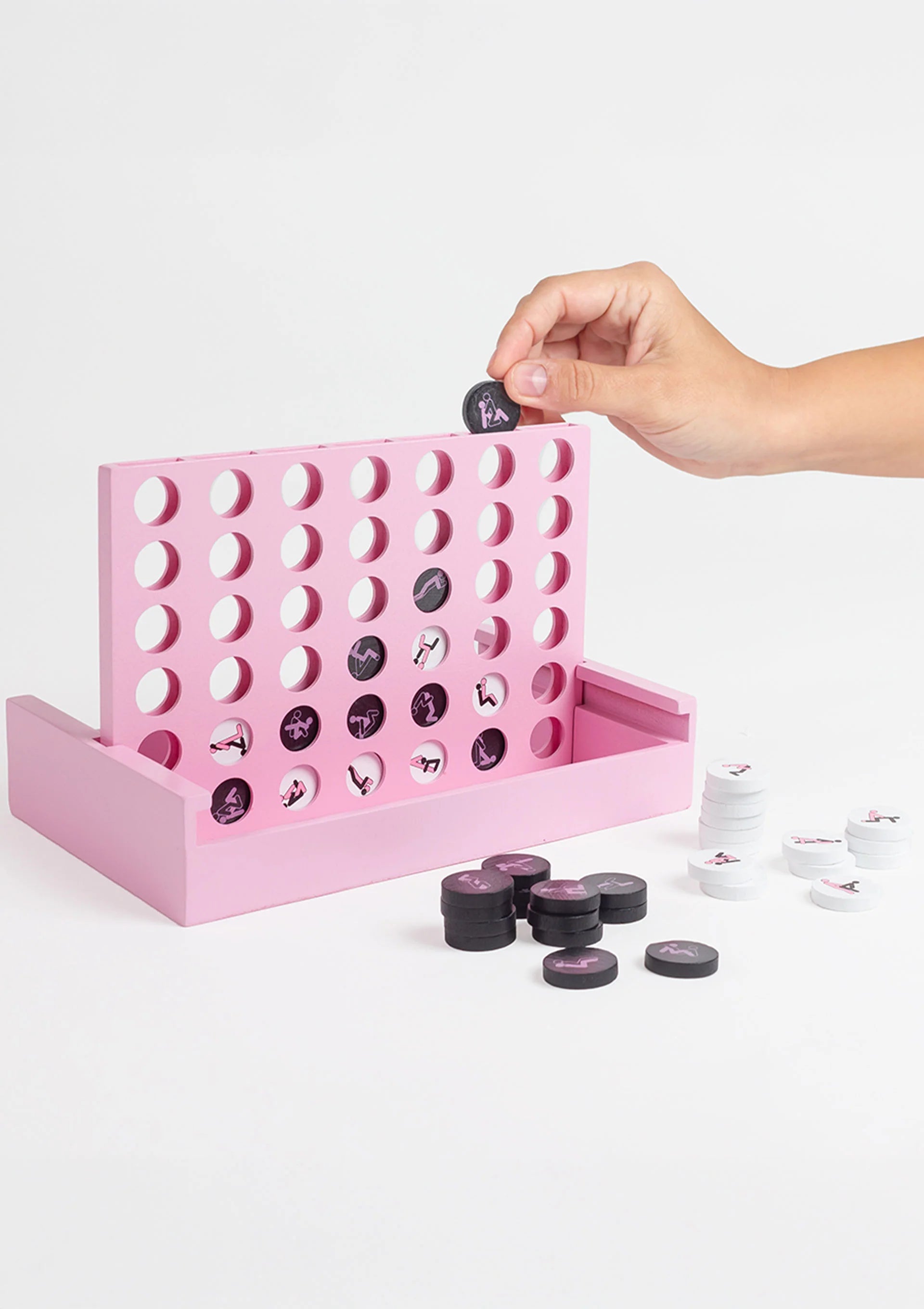 Hand boven de roze rasterplank met zwarte en witte speelschijven