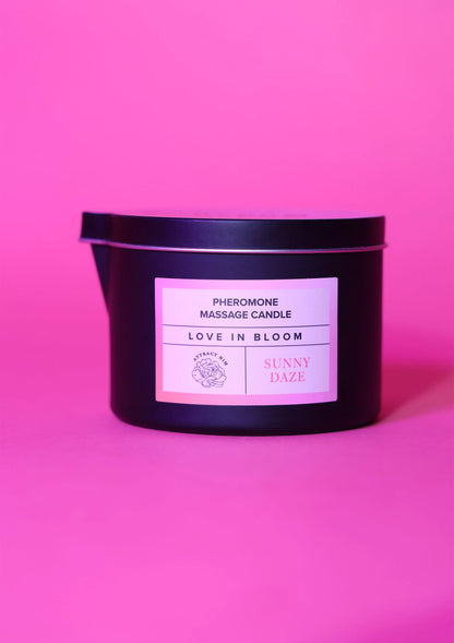 Zwarte massagekaars met etiket Love in Bloom en Sunny Daze, staand in blik.