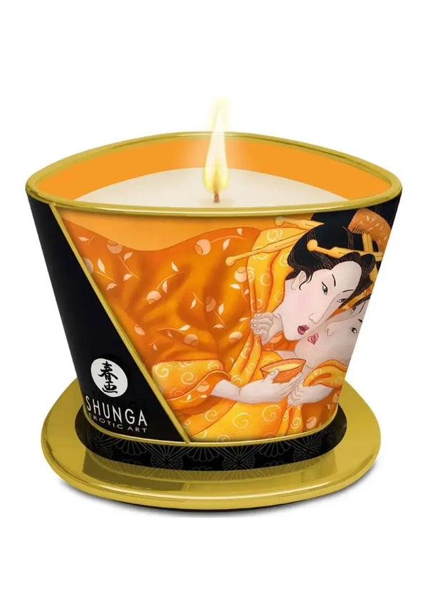 Massagekaars Shunga met oranje illustratie en brandende kaars op gouden voet.