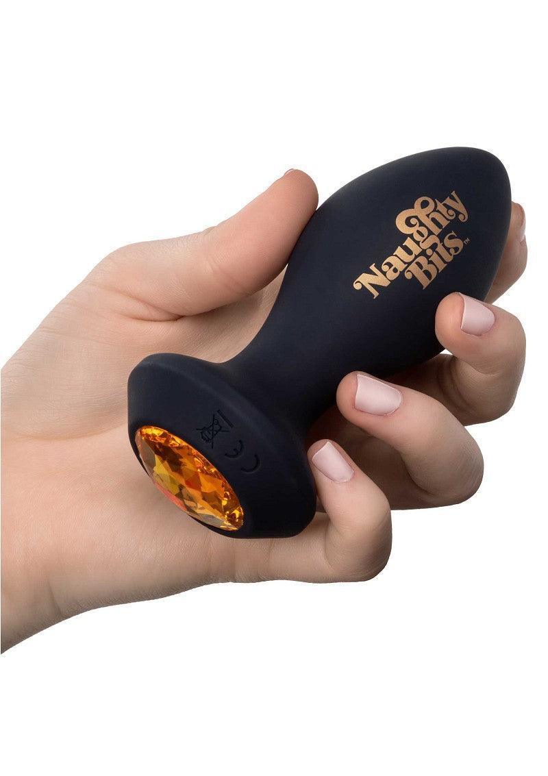 Zwarte vibrerende kontplug met amberkleurige steen vastgehouden in een hand