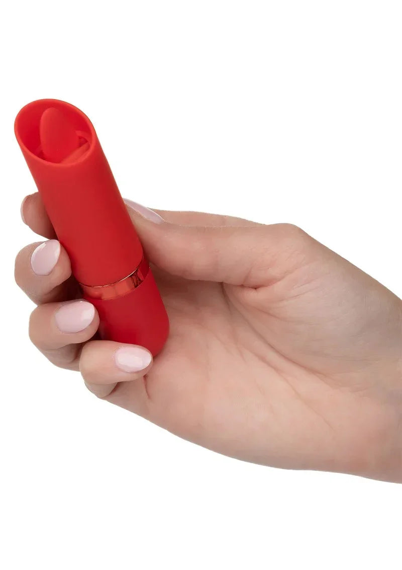 Rode lippenstiftvormige mini vibrator in hand, met ronde dop bovenaan en zwarte ring.