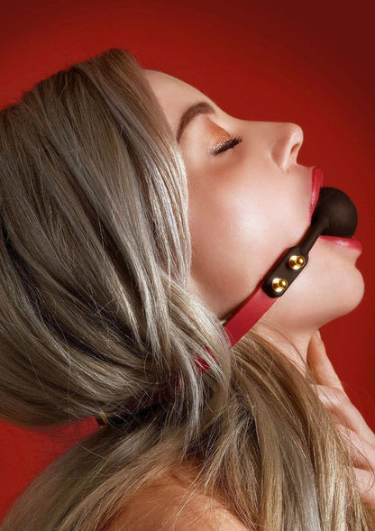 Zwarte siliconen ball-gag met rode band en gouden klinknagels op model
