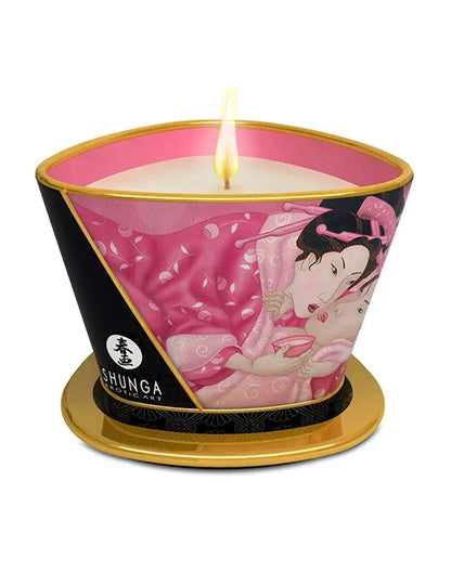 Massagekaars Shunga met roze illustratie en brandende kaars op gouden voet.